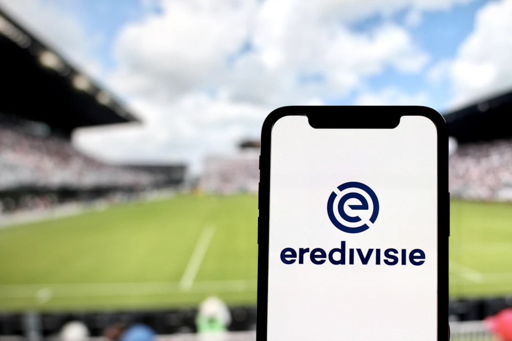 Eredivisie logo on phone with football pitch in the background